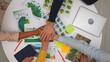 © kinomaster - Top view creative project team meeting in boardroom at desk, discussing ecological project, presenting visual concept graphics, making team hand cheering gesture.