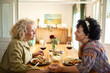 © Marko Geber - Lesbian couple enjoying meal at home in kitchen