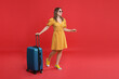 © New Africa - Happy traveller in sunglasses with suitcase on red background