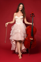 Beautiful woman with cello on red background