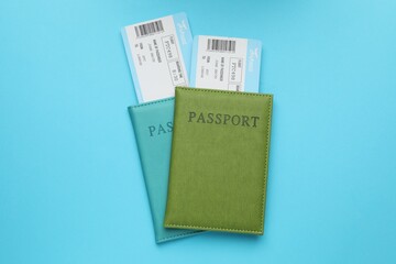 Travel agency. Flight tickets and passports on light blue background, top view