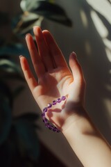 Poster - A hand adorned with a purple bracelet, illuminated by soft sunlight.