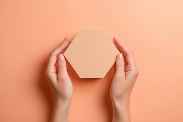 Aufkleber - A person holding a hexagonal object against a soft peach background.