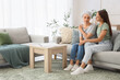 © Pixel-Shot - Young woman with her mother after chemotherapy hugging on sofa at home