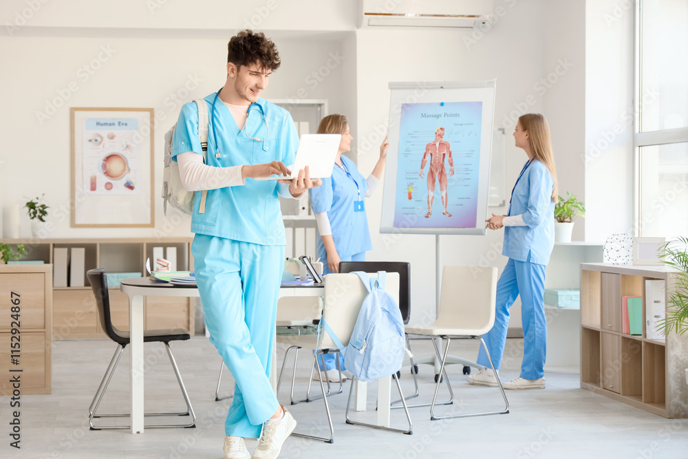 Male medical student studying with laptop at university