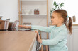 © Pixel-Shot - Cute little girl touching hot stove in kitchen. Child at risk