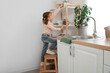 © Pixel-Shot - Cute little girl taking jar of pasta from high shelf in kitchen. Child at risk