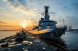© Abdul - Naval ship docked at sunset by the harbor.