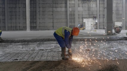 A skilled worker is cutting metal in an industrial environment, creating sparks around him. Clip