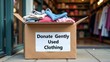 © Evgenii - Donate gently used clothing in a cardboard box outside a thrift store during daylight hours in a bustling urban area
