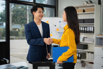 Wall Mural - Business men and women shake hands confidently at an office meeting.