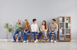 © Studio Romantic - Group of five diverse young people sitting on chairs in row and talking to each other. Team of friends, students or colleagues discussing work or study matters, exchanging ideas and opinions together.