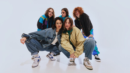 Stylish young people, men and women in oversized jackets, windbreakers and retro sneakers, posing against white studio background. Concept of 90s fashion, youth. Modern take on nostalgic streetwear