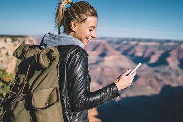 Wall Mural - positive hipster girl sending text message on telephone during hiking tour in grand canyon using goo