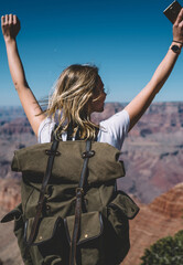 Wall Mural - back view of excited hipster girl standing on high mountain top feeling free raising hands up, happy