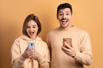 Wall Mural - excited couple checking smartphone  in beige colors. app, social media, connection concept.