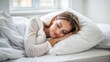 © engincan - Young woman lying in white bed on pillows under blanket, resting head on hands, sleeping peacefully, relaxing after night shift