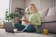 © deagreez - Relaxed blonde woman enjoying leisure at home while taking notes on a cozy day in the living room