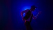 © kinomaster - Man musician in stylish hat dancing on dark concert stage against blue spotlight and singing looking at camera, isolated on black studio background.