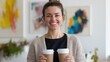 © Pro Hi-Res - Woman smiling while holding two coffee cups in a bright, modern cafe with colorful artwork on the walls.