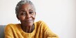© Сергей Захаров - nostalgic 75-year-old african american woman wearing cozy knitted sweater sitting on chair with wistful smile gazing