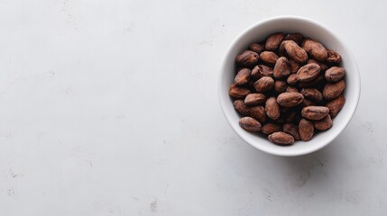 Wall Mural - Raw cacao beans in white bowl on light background showcasing rich texture and natural color ideal for culinary or health-related projects