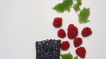 Canvas Print - Raspberries and fresh leaves arranged artistically on a clean background creating a vibrant and colorful natural composition