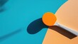 © VirtualVista - Ping pong paddle and orange ball resting on a vibrant blue and orange table surface showcasing recreational sport equipment and playful design
