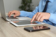 © New Africa - Businessman with tablet, smartphone and laptop at wooden table, closeup. Modern technology
