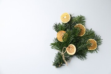 Wall Mural - Christmas bouquet of fir tree branches with dry orange pieces on light background, top view. Space for text