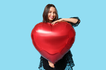 Canvas Print - Beautiful young woman with heart shaped air balloon on blue background. Valentine's Day celebration