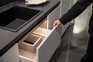 Wall Mural - A woman opens a drawer in a contemporary kitchen, revealing organized compartments