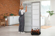© Pixel-Shot - Female worker repairing refrigerator in kitchen