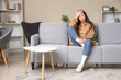 © Pixel-Shot - Portrait of worried young woman sitting on sofa