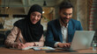 © Yuliia - Male female teamwork Arabian man muslim woman in hijab girl guy businessman businesswoman two happy business colleagues coworkers managers analyzing marketing graphs documents in office typing laptop
