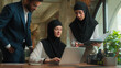© Yuliia - Business partners coworkers Arabian man businessman Muslim women in hijab businesswomen consultation mentor help intern in office check laptop work project multiethnic teamwork corporate education