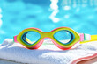 © romanets_v - Colorful swimming goggles on towel by poolside in sunlight