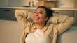 © Yuliia - Happy relaxed African American woman female home owner joyful girl renter tenant sit on couch relax enjoy house renovation moving in new apartment relocation day buy rent real estate mortgage smile