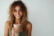 © hkjdesign - A young woman with long, wavy hair smiles while holding a smoothie.