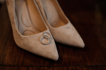 Wall Mural - Elegant Wedding Shoes with Silver Rings on a Wooden Table