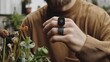 © alva studio - Close-up of a man's hand wearing two black rings, one with a square button, near plants.