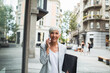 © Davor - Senior businesswoman using smartphone downtown in city