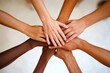 © HO - A business team in a meeting, stacking their hands together to signal commitment and shared vision.