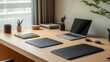 © makappa - Minimalist home office workspace with laptop, stationery, and desk mats on a light wood desk.
