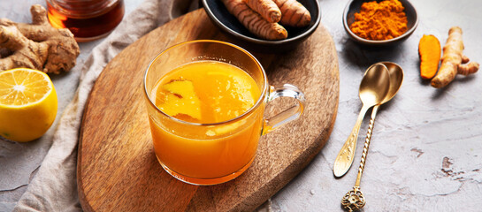 Wall Mural - Healthy turmeric golden tea on light gray background.