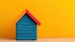 © CoreVisuals - housing crisis demand concept. Colorful toy house against a bright yellow background.