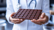 © Helena - Doctor holding a dark chocolate bar in medical setting