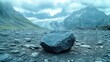 © AFFANYUDA - Gray boulder rests on a rocky landscape, mountains and glacier in the distance.
