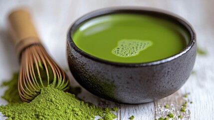 Matcha tea in a bowl with whisk and powder.