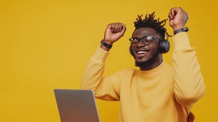 Wall Mural - a man in a yellow shirt is wearing headphones and smiling while using a laptop. concept of happiness